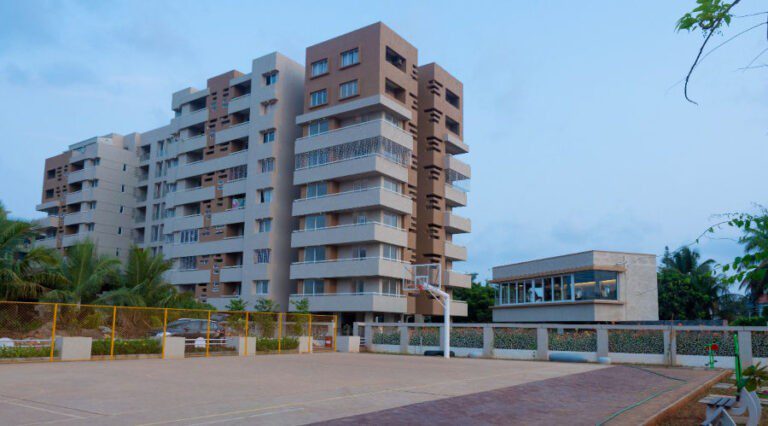Exteririor shot of an apartment with a basketball court in front of it